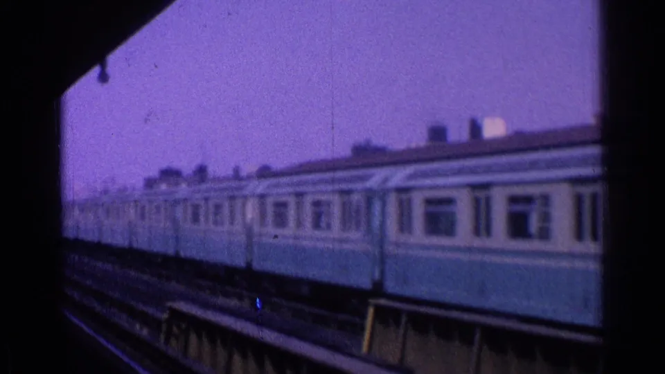 Close platform view of blue-and-cream passenger railcars on elevated tracks in 1965 Ohio home-movie footage.