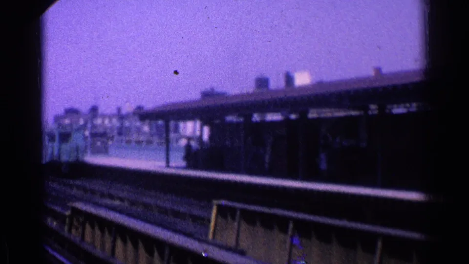 1965 Ohio rail-station view from a moving train, with a platform canopy, tracks, and part of a pale passenger car.