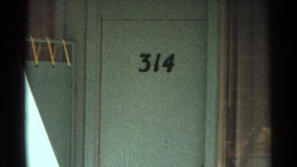 Close 1968 Scottsdale motel detail showing the door number 314, turquoise wall surface, adjacent curtains, and partial railing.