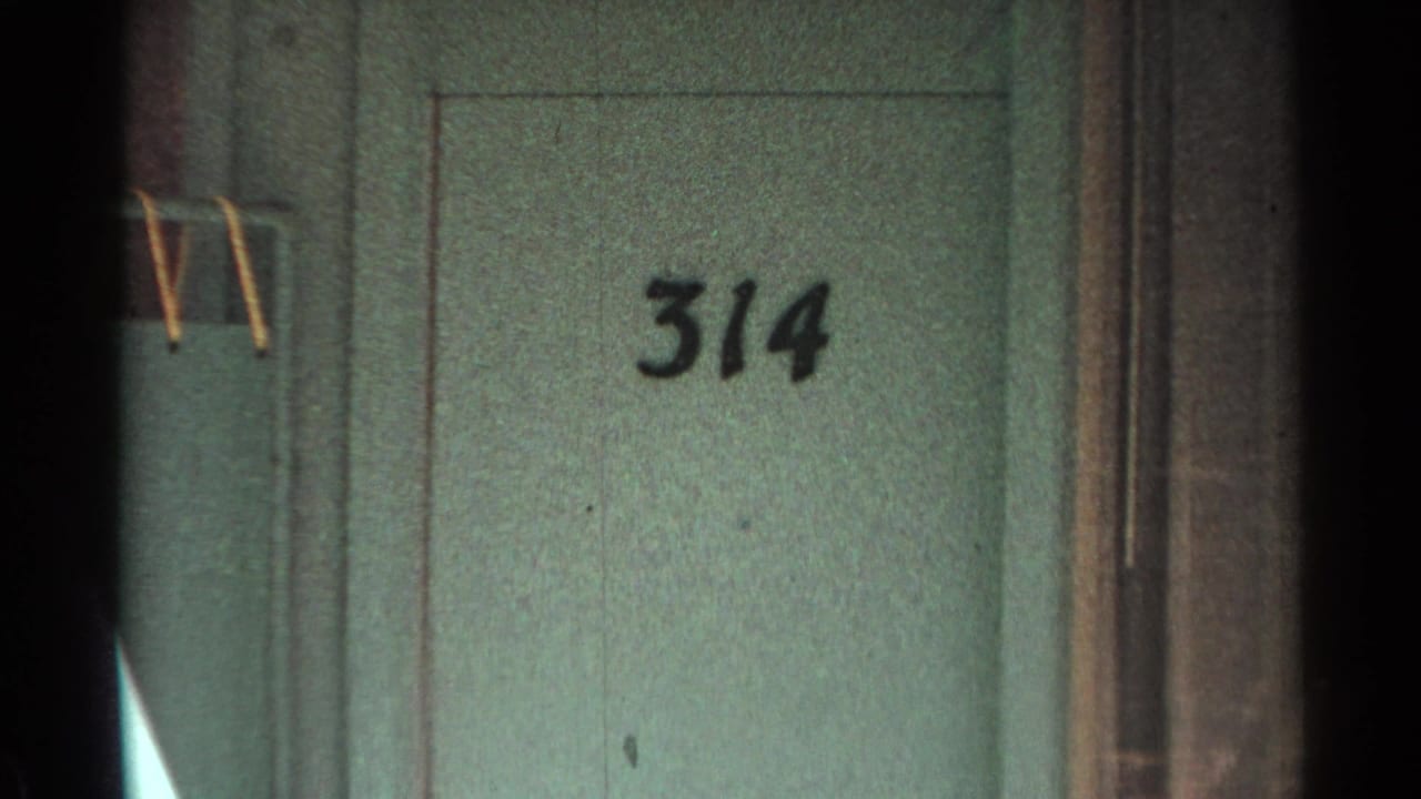 Green motel door marked 314 beside a partial outdoor chair or bench.