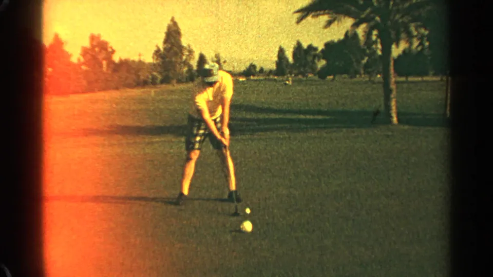 In Scottsdale, Arizona, 1968, a man in a hat and plaid shorts stands over a golf ball on a sunlit course.
