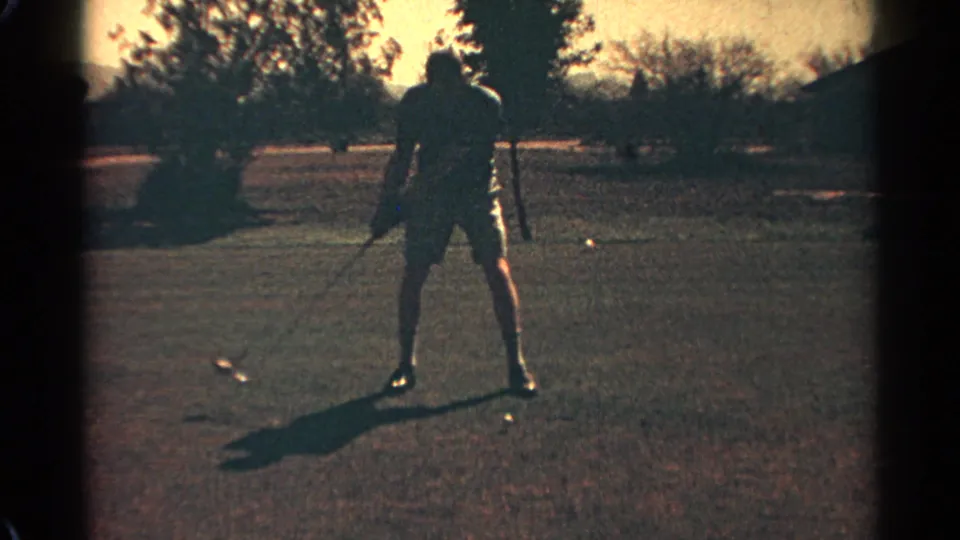 Seen from behind, the golfer addresses the ball on a Scottsdale fairway, with long shadows and trees in the background.
