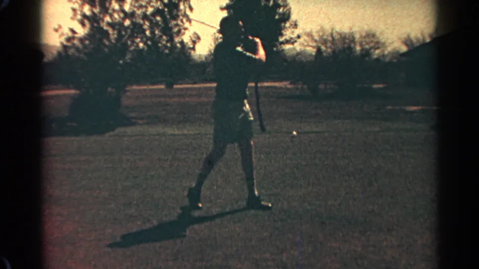 A man continues his golf swing on a Scottsdale course, silhouetted against warm 1968 home-movie light.