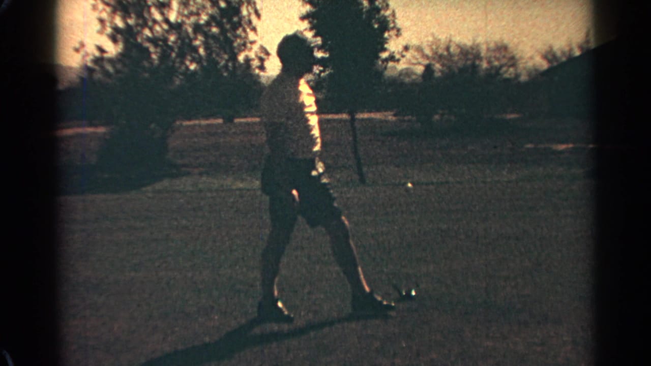 In metadata-supported 1968 Scottsdale, an adult golfer in a white hat stands on grass with a club, partly silhouetted by strong sun.
