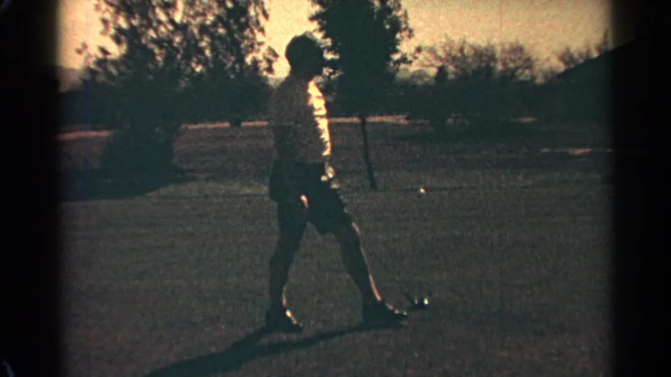 In metadata-supported 1968 Scottsdale, an adult golfer in a white hat stands on grass with a club, partly silhouetted by strong sun.