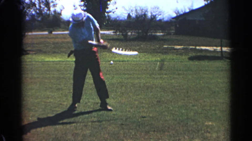 In 1968 Scottsdale, the golfer follows through with the club extended while a ball rests or moves on the grass ahead.