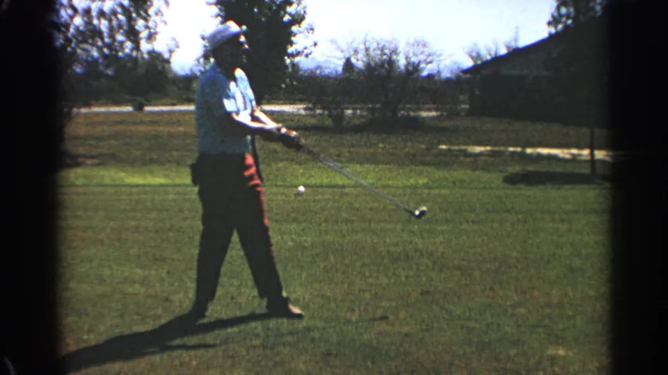 The 1968 Scottsdale home-movie frame shows the golfer lowering his club after the swing while watching the course.