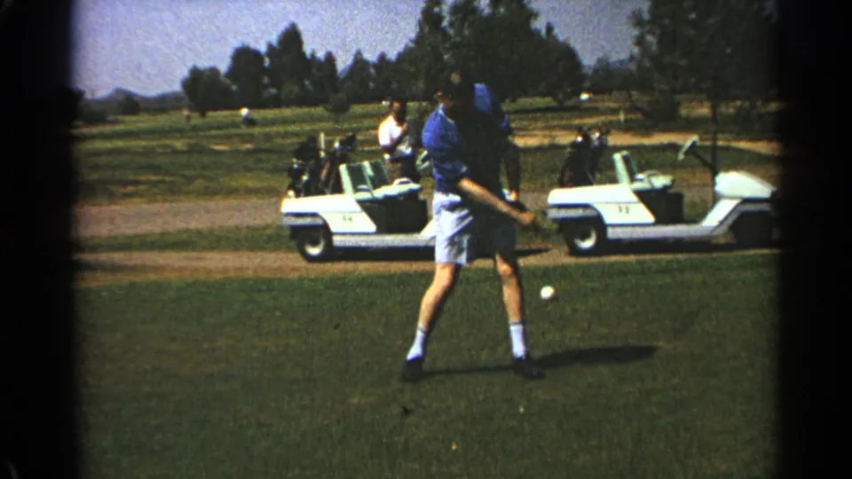 The Scottsdale golfer follows through on his swing as two white golf carts sit behind him on the course.