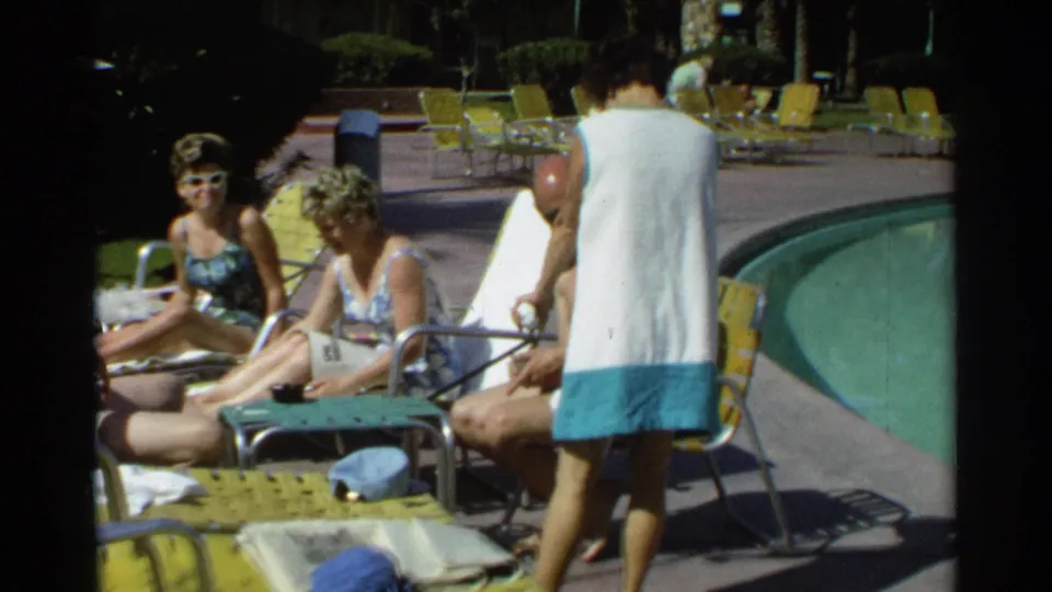 1968 Scottsdale poolside scene with adults in sunglasses and swimsuits relaxing on yellow lounge chairs as a woman in a white-and-blue cover-up passes.