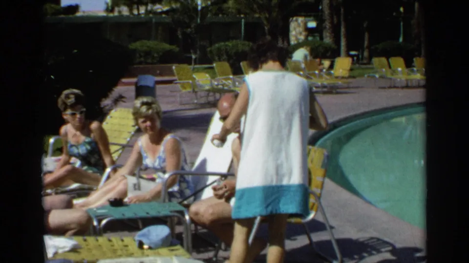 Adults at a Scottsdale resort pool sit and converse on yellow lounge chairs, with the green pool and a woman in a cover-up visible nearby.