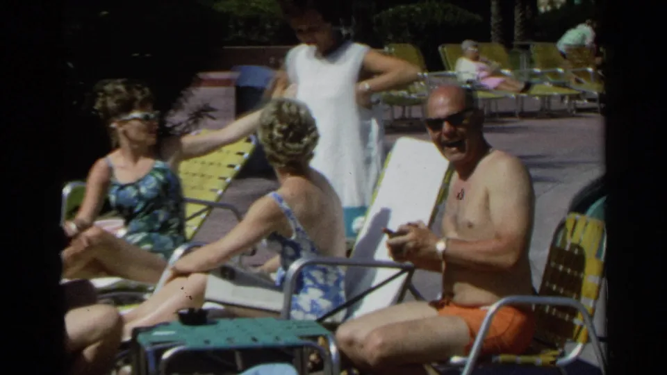 1968 Scottsdale home-movie frame of adults in swimsuits relaxing on yellow and green lounge chairs in bright sun.