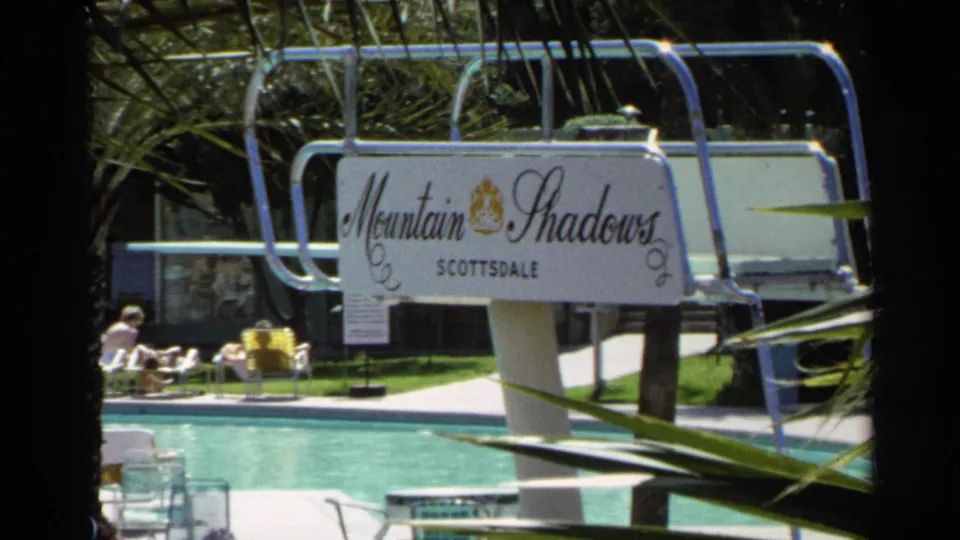 1968 Scottsdale pool area framed by palms, with guests on lounge chairs and a visible Mountain Shadows Scottsdale sign.