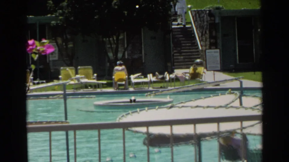1968 Scottsdale poolside detail with lounge chairs, stone steps, bougainvillea, railings, and a distant guest near the building.