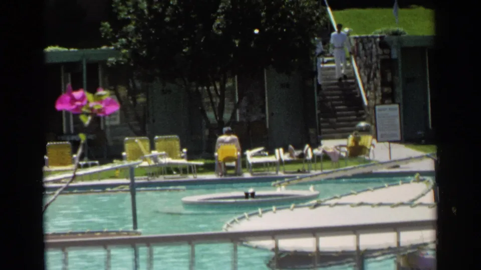 Scottsdale pool courtyard with bougainvillea, yellow lounge chairs, railings, stone steps, and a distant person in white near the stairs.