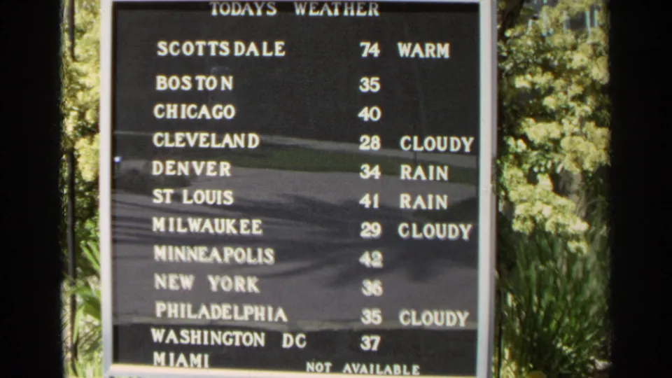 1968 Scottsdale home-movie frame showing a weather board comparing U.S. city temperatures, with Scottsdale listed at 74 and warm.