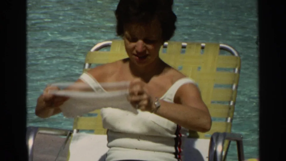 An adult woman in swimwear sits beside the Scottsdale resort pool in 1968, drying off with a white towel on a yellow lounge chair.