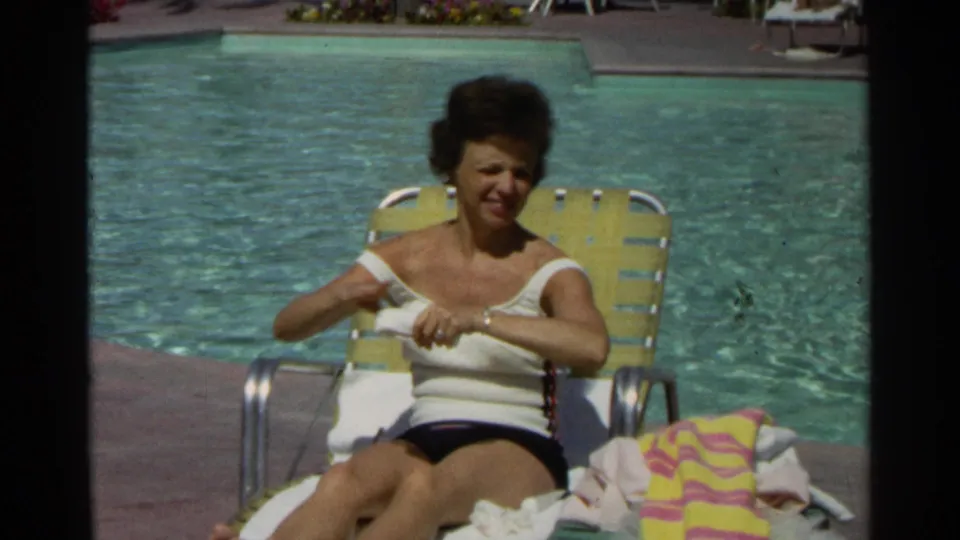 A woman in a white swimsuit and dark shorts sits on a yellow lounge chair beside a Scottsdale pool in 1968.