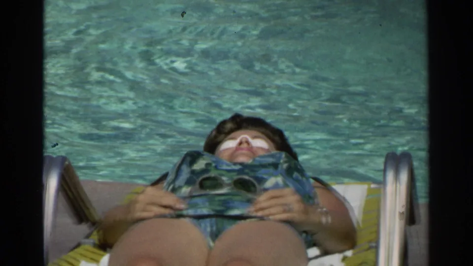 In the final frame, the woman reclines beside the Scottsdale pool, holding sunglasses as she sunbathes in 1968 footage.