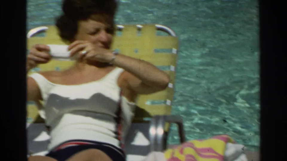 In supplied 1968 Scottsdale footage, a woman in a white swimsuit sits on a yellow lounge chair by the pool.