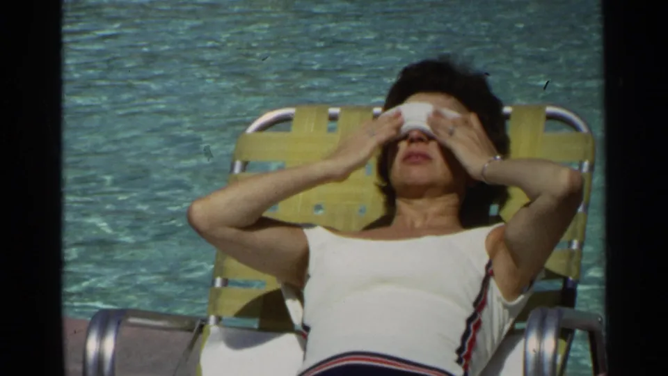 In supplied 1968 Scottsdale footage, a woman reclines poolside while positioning a white eye mask over her eyes.