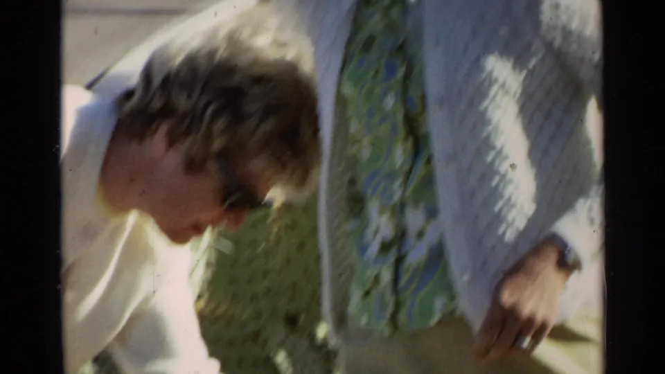 A close home-movie frame shows one woman leaning toward a cactus while her companion stands beside her in Scottsdale, Arizona.