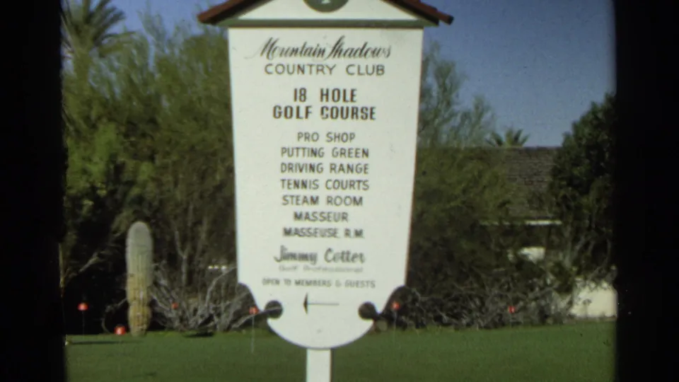 Mountain Shadows Country Club sign in Scottsdale, Arizona, with 18-hole golf course text, green lawn, cactus, and desert plants visible.