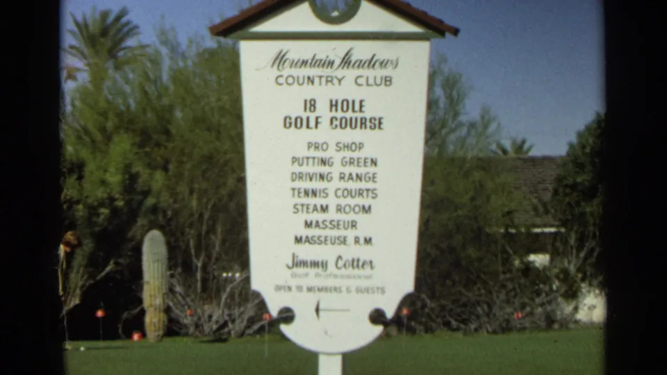 1968 home-movie view of the Mountain Shadows Country Club sign, with listed amenities, desert landscaping, and a partly visible golfer at left.