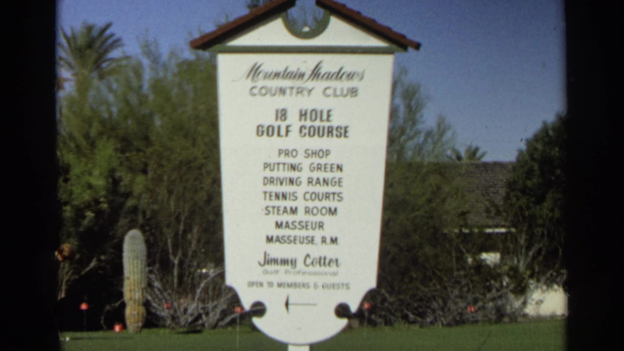 Country club sign with golf amenities listed, surrounded by lawn and desert landscaping.