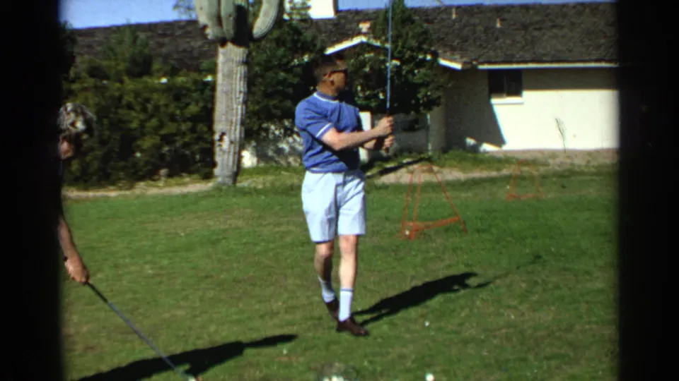 In the 1968 Scottsdale backyard footage, the man holds his club as another adult golfer enters the edge of the frame.