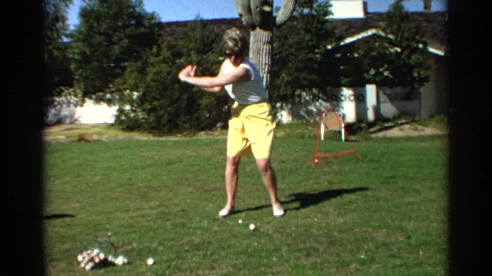 A 1968 home-movie frame shows the woman mid-swing on grass, with a ball basket, shrubs, cactus, and home exterior in the background.
