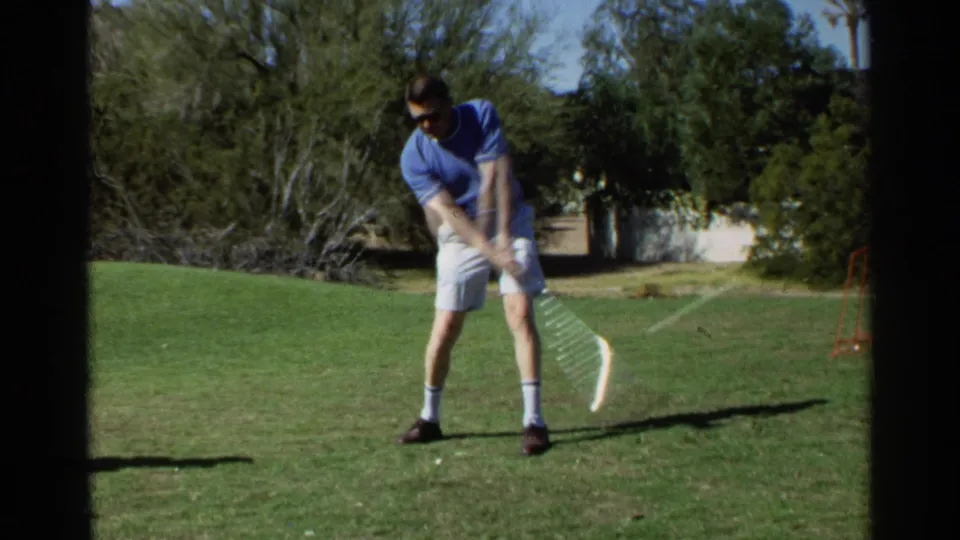 Adult man in sunglasses stands on a sunlit golf area with his club extended after a swing, matching the Scottsdale 1968 metadata.