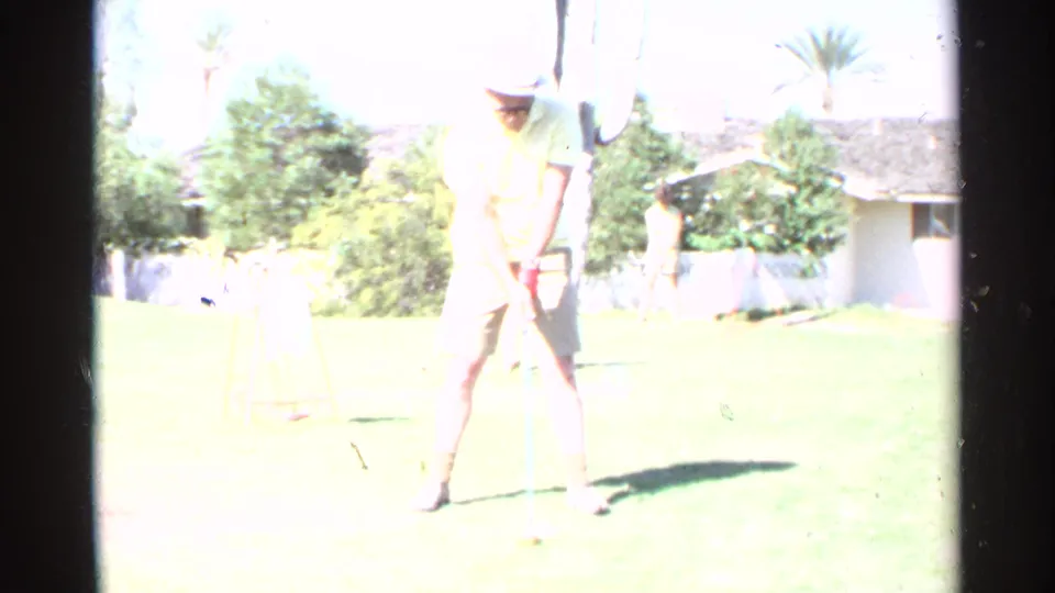 A bright 1968 home-movie frame shows the golfer standing over a ball on the backyard grass, with the residential setting partly washed by exposure.