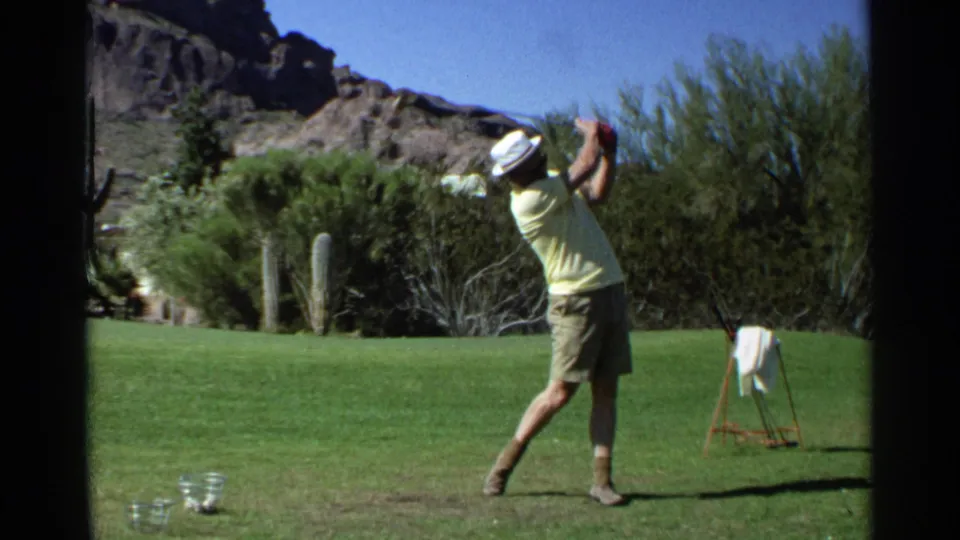 The golfer follows through on a tee shot at a Scottsdale desert course, with cacti and brush behind the fairway.