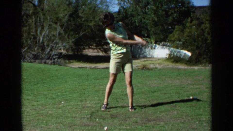 In 1968 Scottsdale home-movie footage, a woman in a green top and khaki shorts follows through on a golf swing.