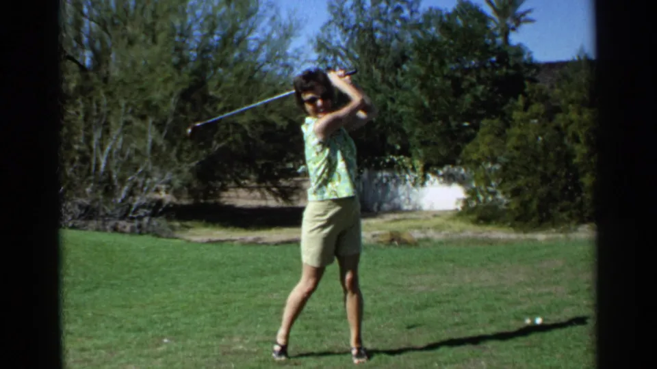 The woman turns toward the camera with her club raised in the Scottsdale golf practice scene from 1968.