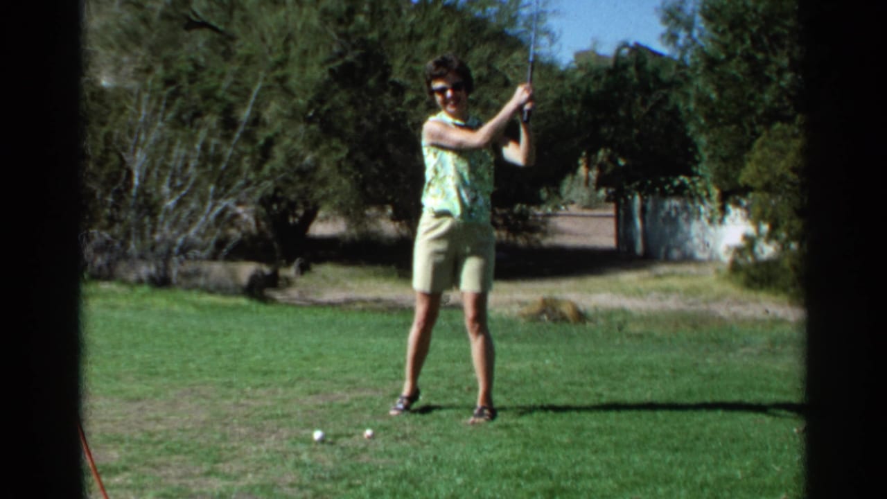 A woman in sunglasses stands on a Scottsdale golf course in 1968, holding a club with trees and bright sky in the background.