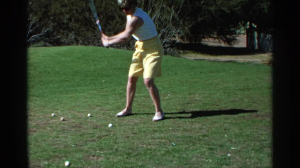 The woman continues her golf swing in Scottsdale, Arizona, with motion blur and a dark 8mm frame edge visible.