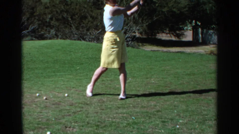 At the end of the 1968 Scottsdale practice swing, the woman stands in follow-through with her shadow stretching across the grass.