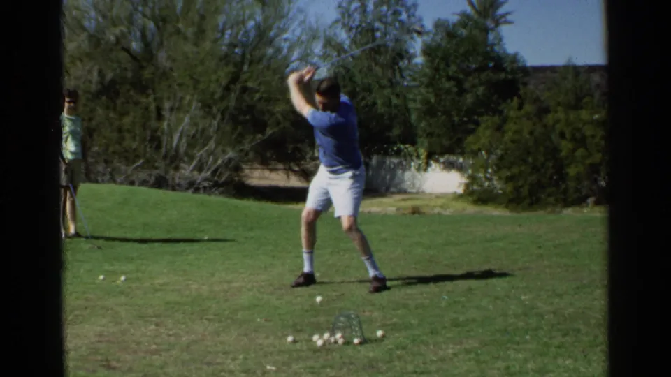 In the 1968 Scottsdale backyard footage, the man raises his golf club during practice beside a pile of golf balls on the lawn.
