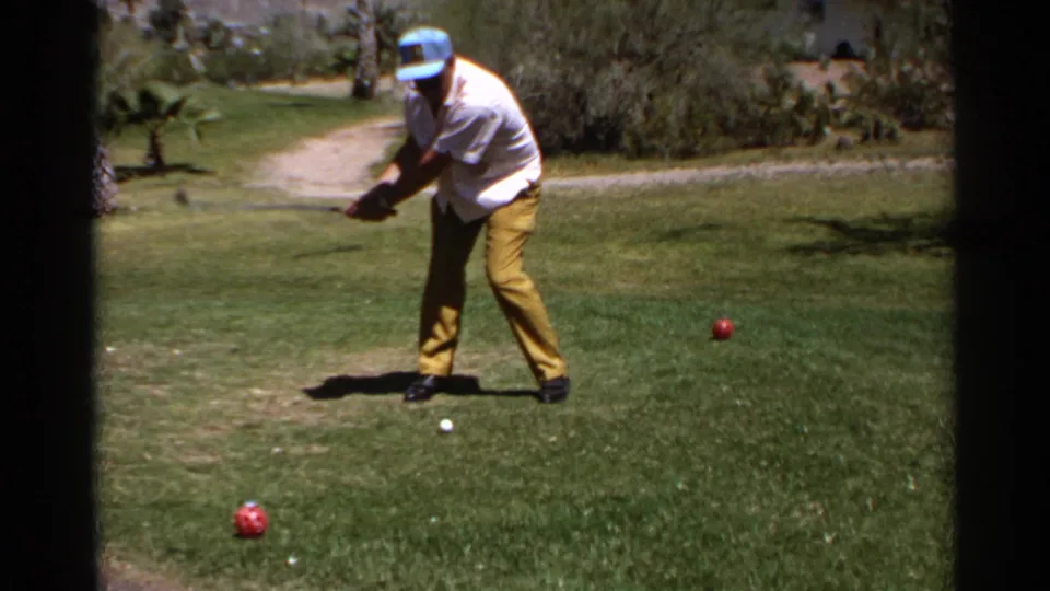 The golfer starts his swing on a Scottsdale fairway, with a white ball below him and red marker balls set in the grass.