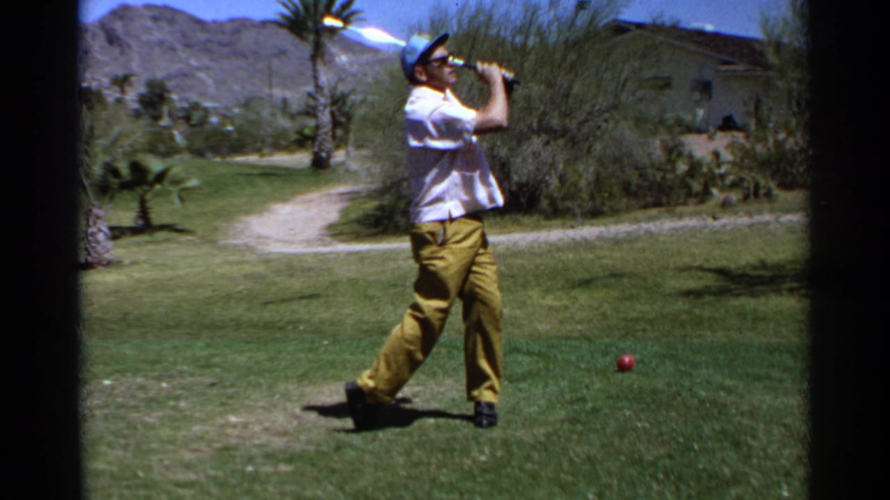 Young man in a white shirt, yellow trousers, and blue cap follows through on a golf swing in 1968 Scottsdale, Arizona.