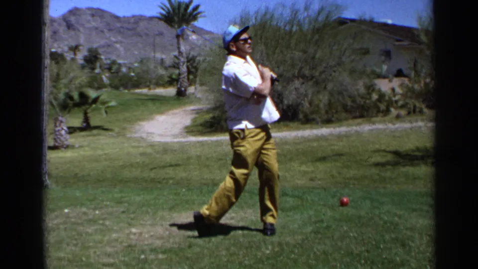 Young golfer pauses after a swing on a Scottsdale golf course, with desert landscaping and mountains visible behind him.