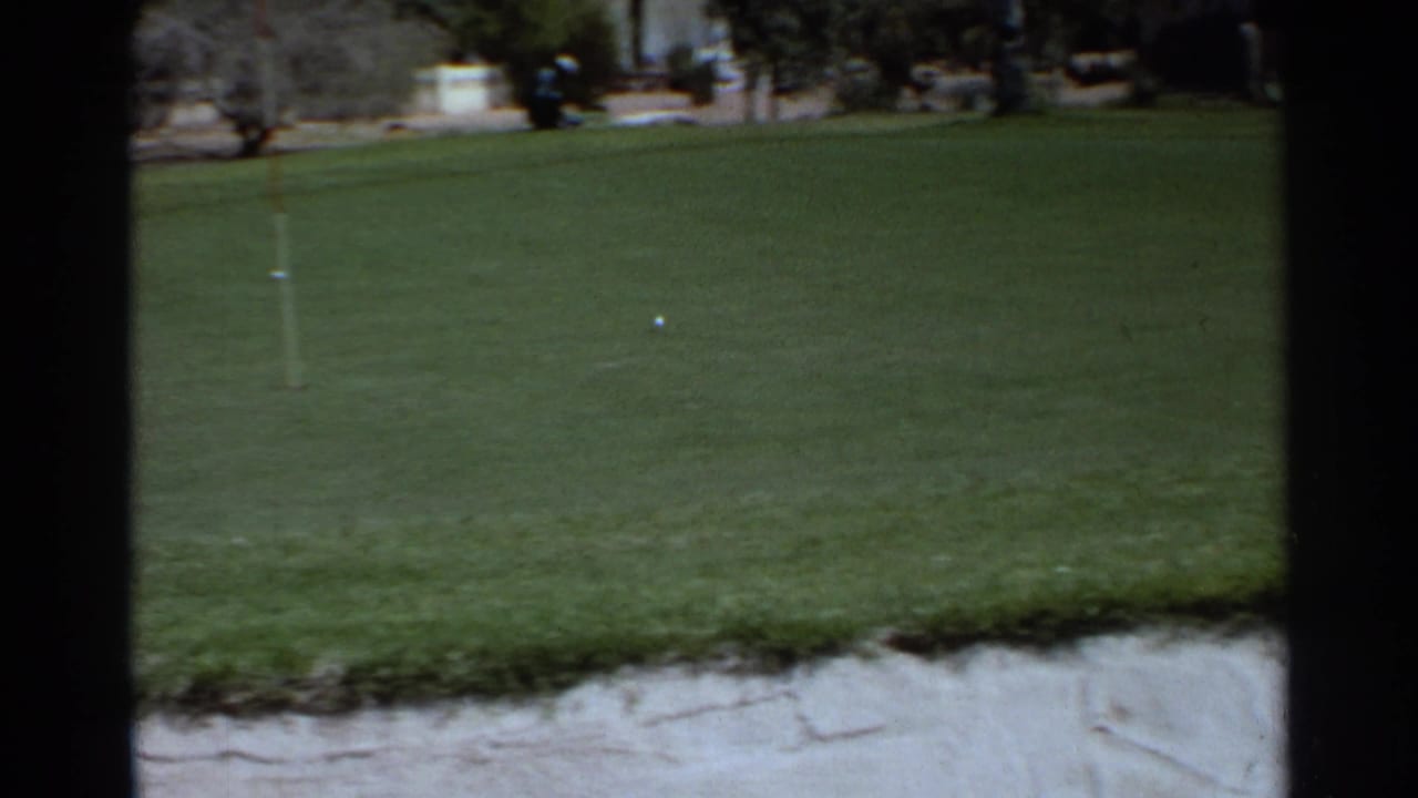 A Scottsdale golf course green shows a flagstick, ball, sand trap edge, and trees in 1968 8mm footage.