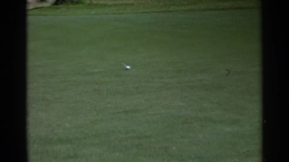 A golf ball rests on a wide green in the Scottsdale course scene, with soft 8mm color and minimal background detail.