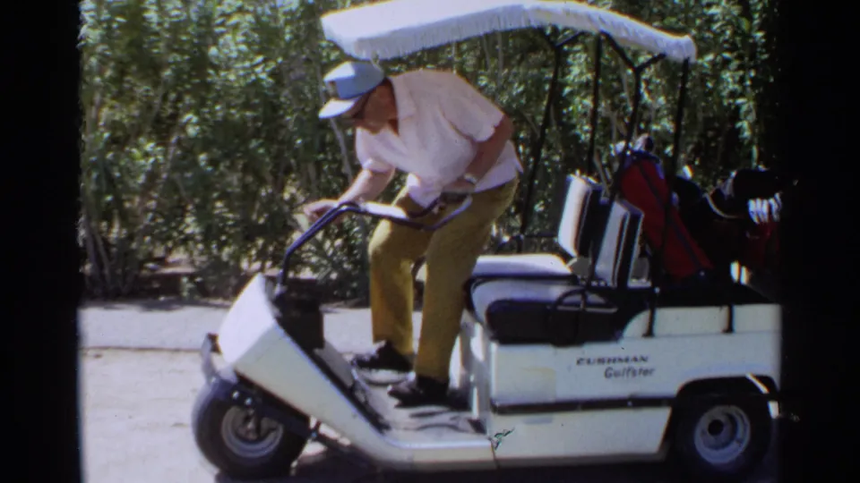 The golfer steps onto the white cart in the 1968 Scottsdale home movie, with the bag and clubs visible behind him.