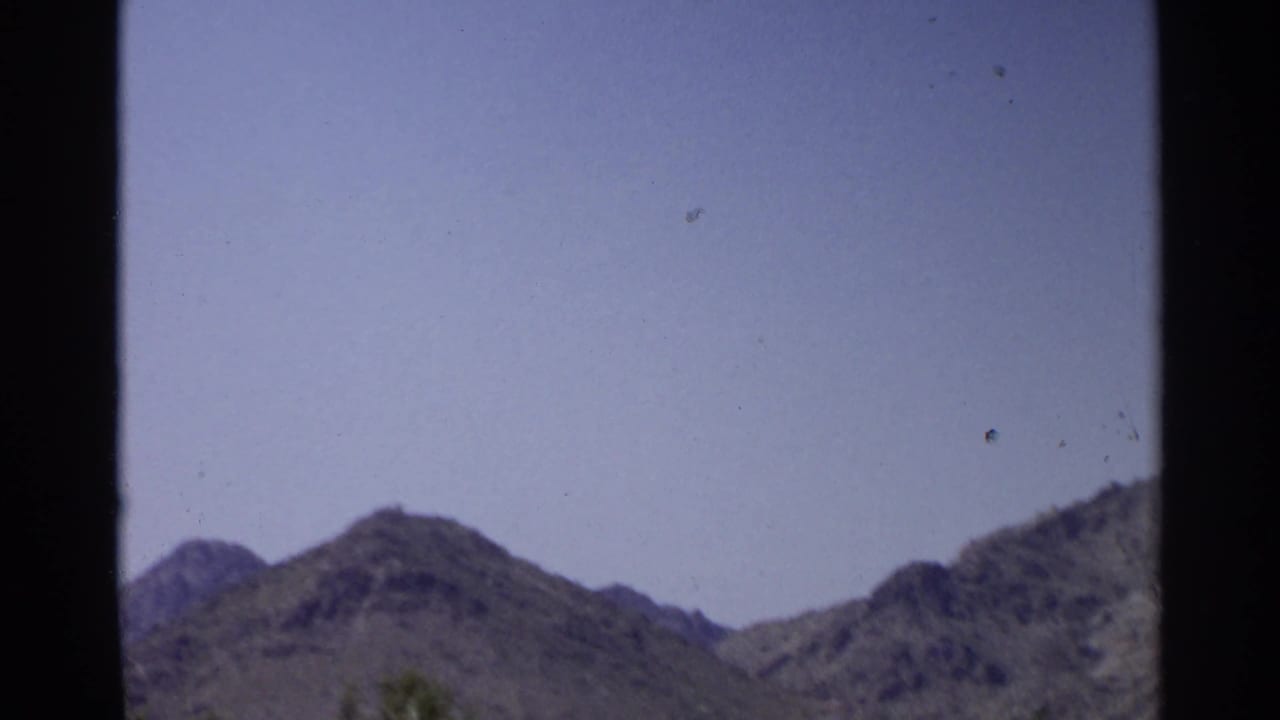 1968 Scottsdale home-movie frame showing hazy sky and desert mountains before the golf-course view appears.