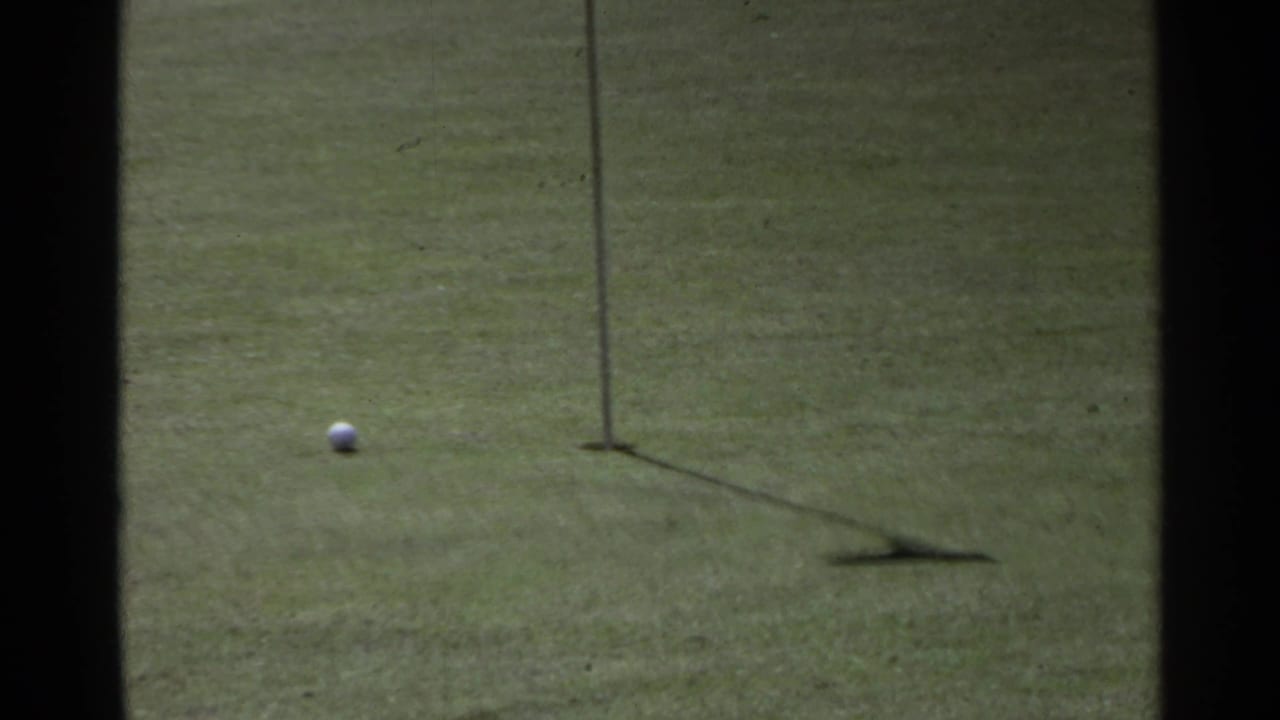 Golf ball near a hole flag on a putting green.