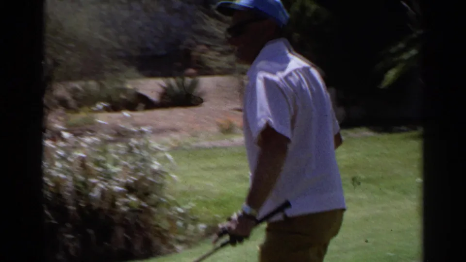 The golfer is seen from behind on the edge of the green, holding a putter beside shrubs and desert landscaping in Scottsdale.