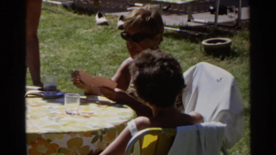 Close poolside frame of children at a floral table with a woman nearby, lounge chairs and grass visible in the 1968 Scottsdale setting.