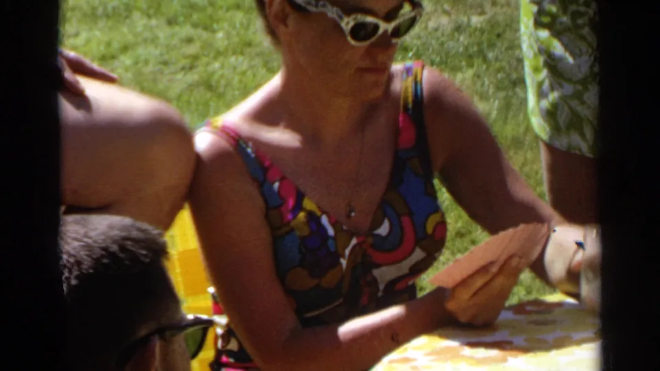 Woman in a colorful 1960s swimsuit and white cat-eye sunglasses holds playing cards outdoors in Scottsdale, 1968.